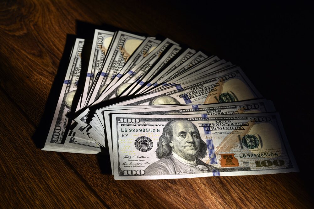 A stack of US dollars scattered on wooden boards