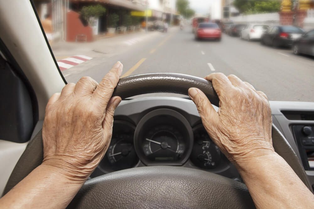 Senior woman driving a car on street in city.