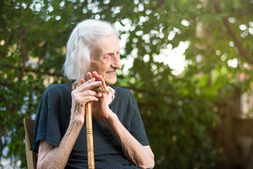 Cheerful senior woman sitting with a walking cane