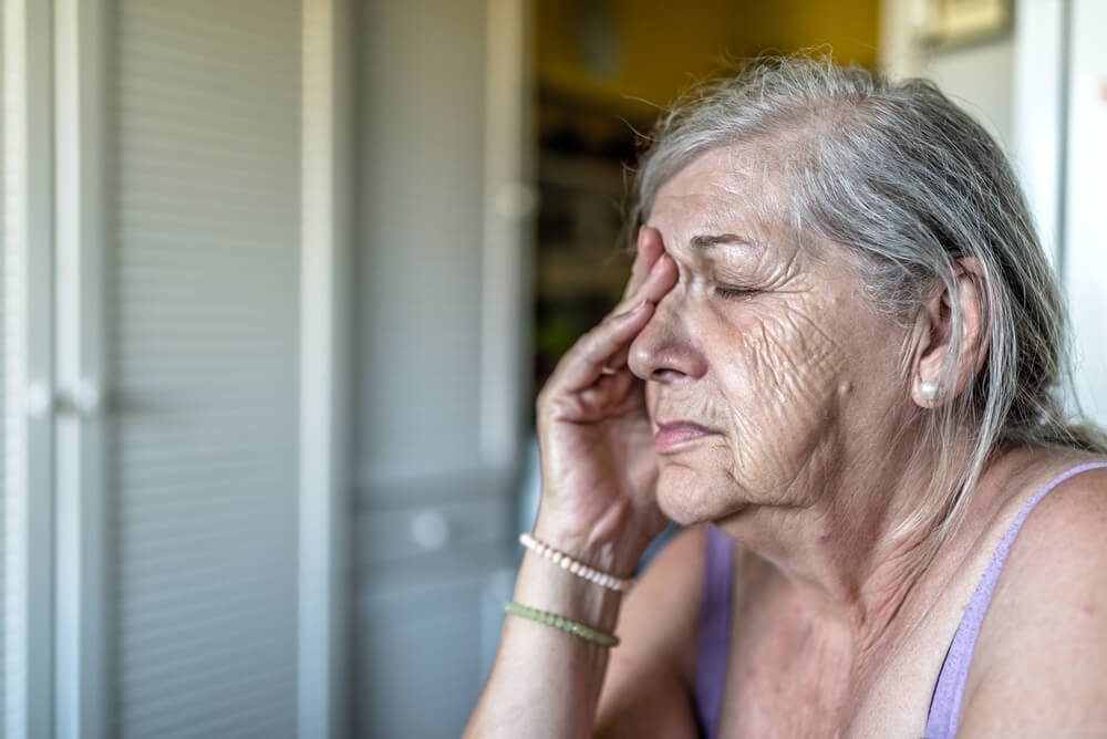 Sad depressed, stressed, thoughtful, senior, old woman, gloomy, worried, covering her face. Senior woman portrait. Saddened and afraid older woman is touching face