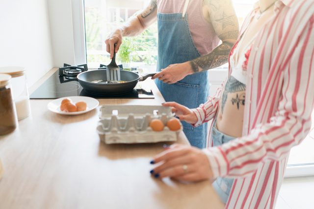 couple making breakfast together in kitchen at home