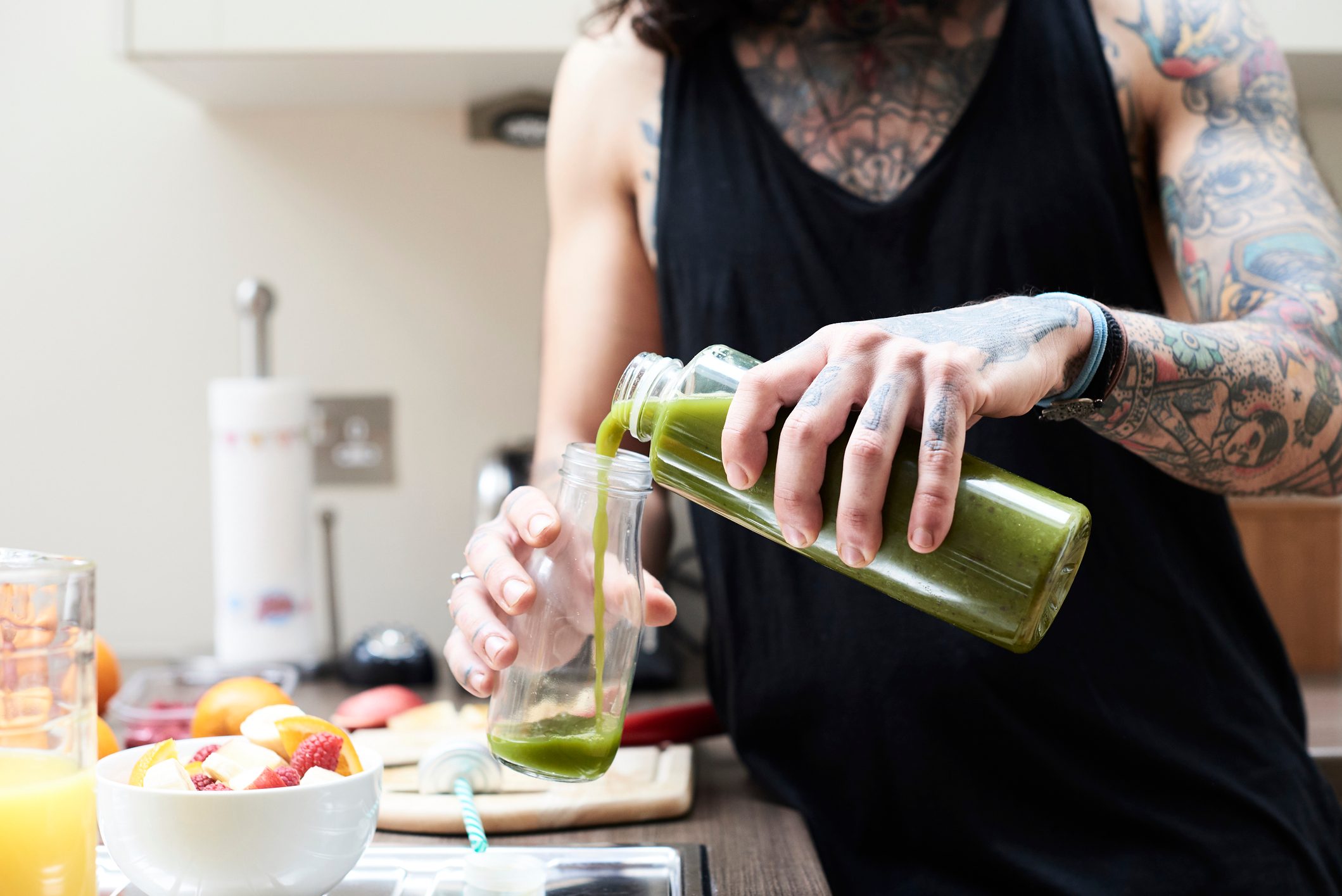 man pouring green juice into glass