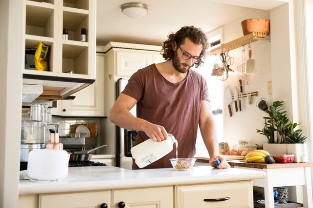 man pouring milk into bowl