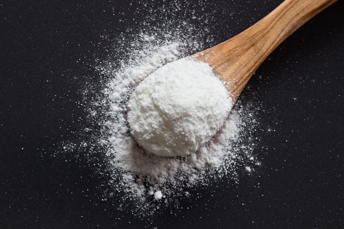Baking soda on a wooden spoon on dark background, top view, sodium bicarbonate, powder, natural, cooking, baking,