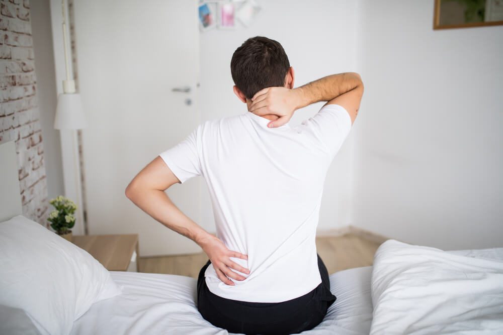 Man suffering from back pain at home in the bedroom.