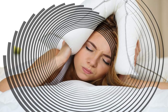 woman holding a pillow over her head, eyes closed