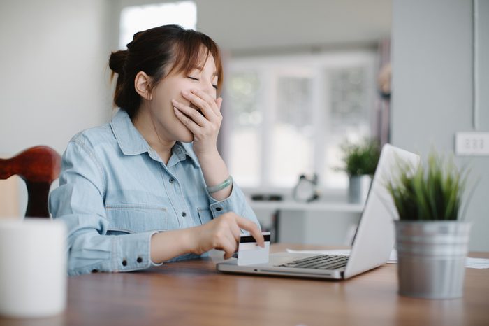 Tired sleepy woman yawning, working at office desk and holding credit card, overwork and sleep deprivation concept