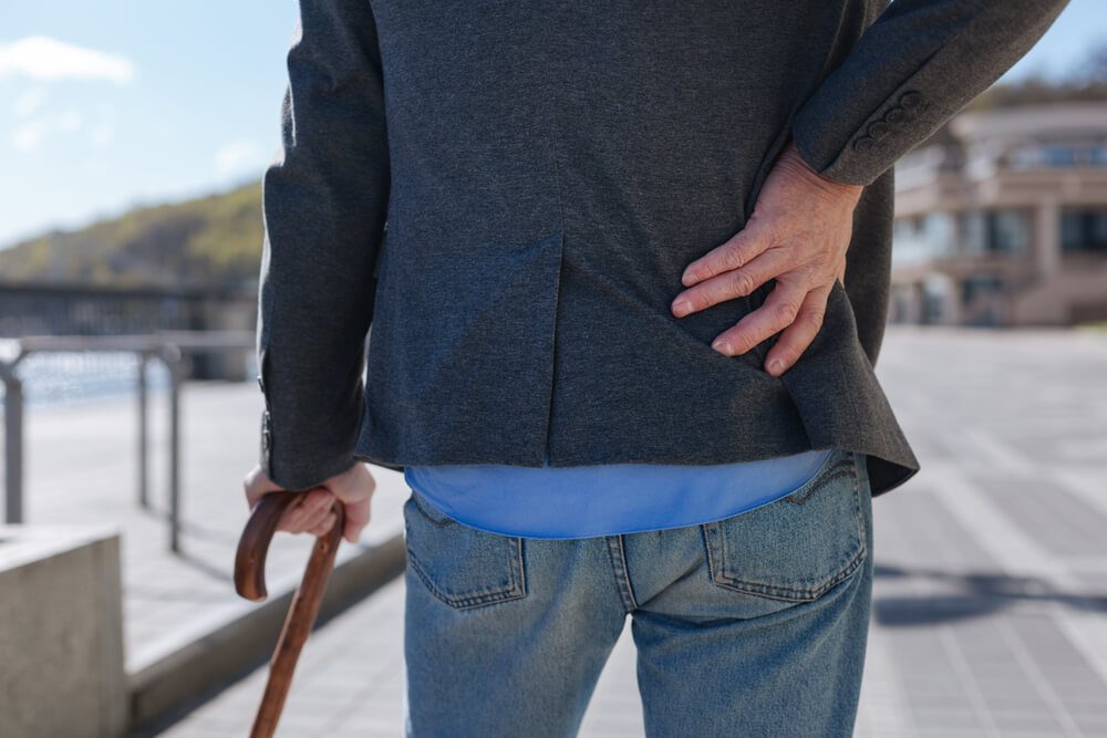 Stylish man feeling pain in his back outdoors