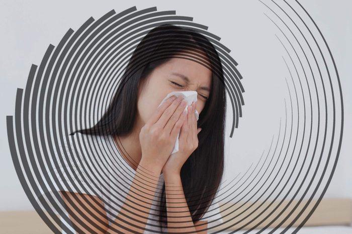 asian woman sneezing into a tissue