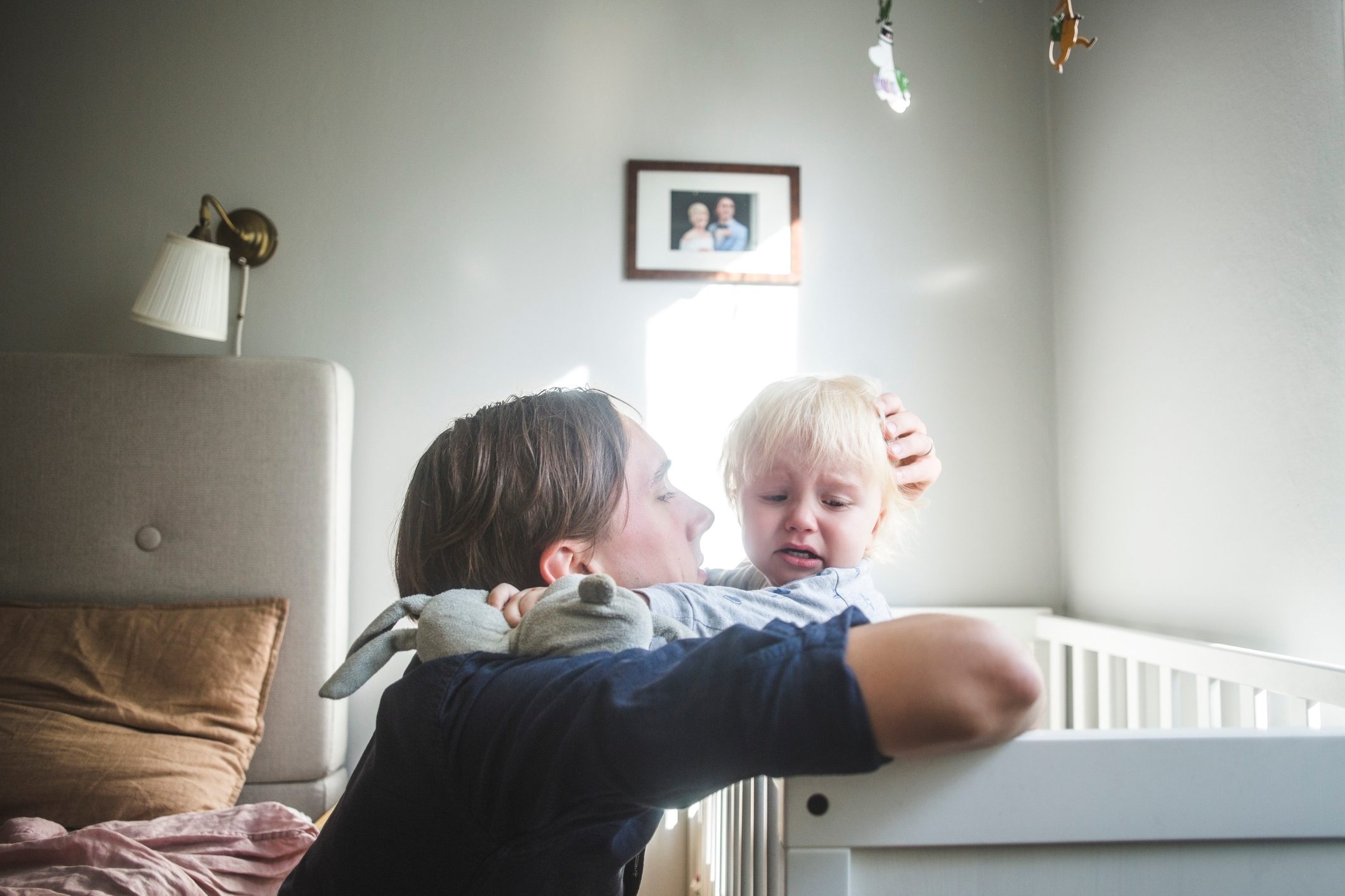 father consoling crying baby in crib at home