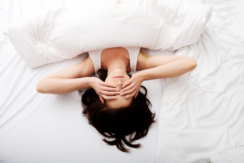 Sleepy brunette woman waking up and rubbing her eyes.