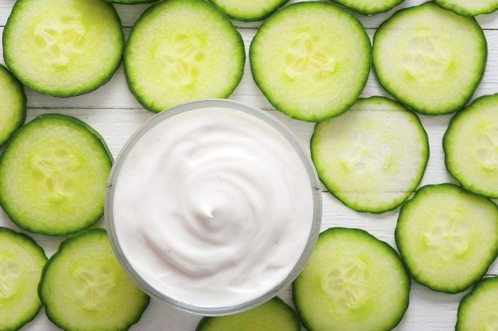 face mask with cucumber slices, white wood background