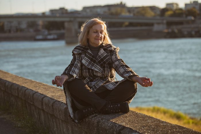 Woman meditating in the sun by the river.