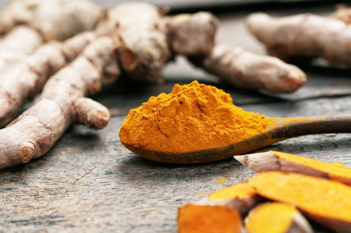 Turmeric powder on wooden spoon.