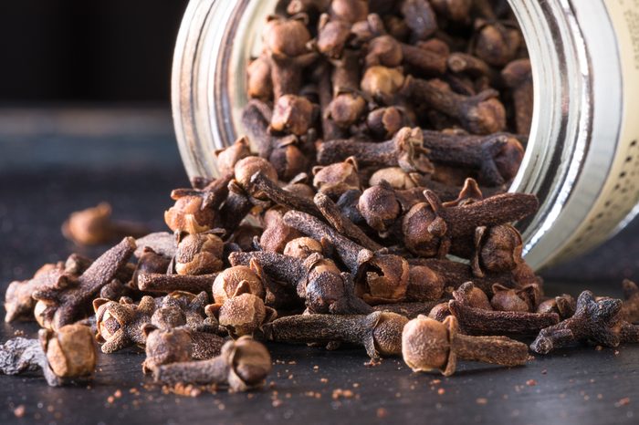 Whole cloves spilling from a spice jar