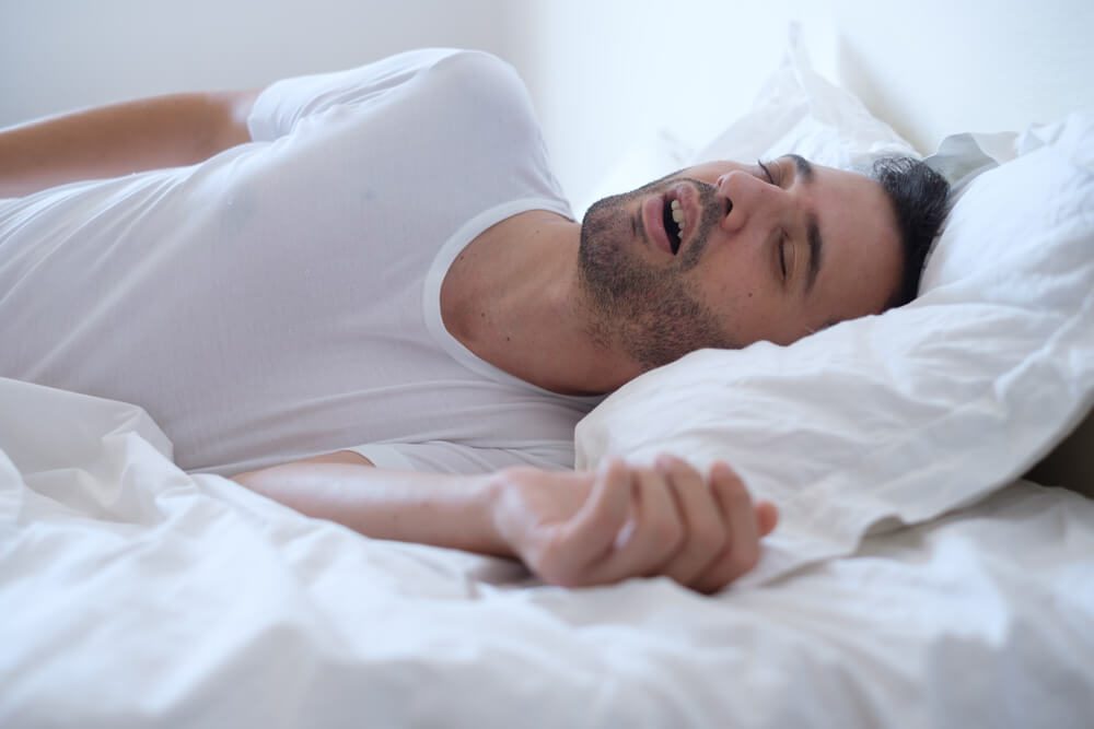 Man snoring because of sleep apnea lying in the bed