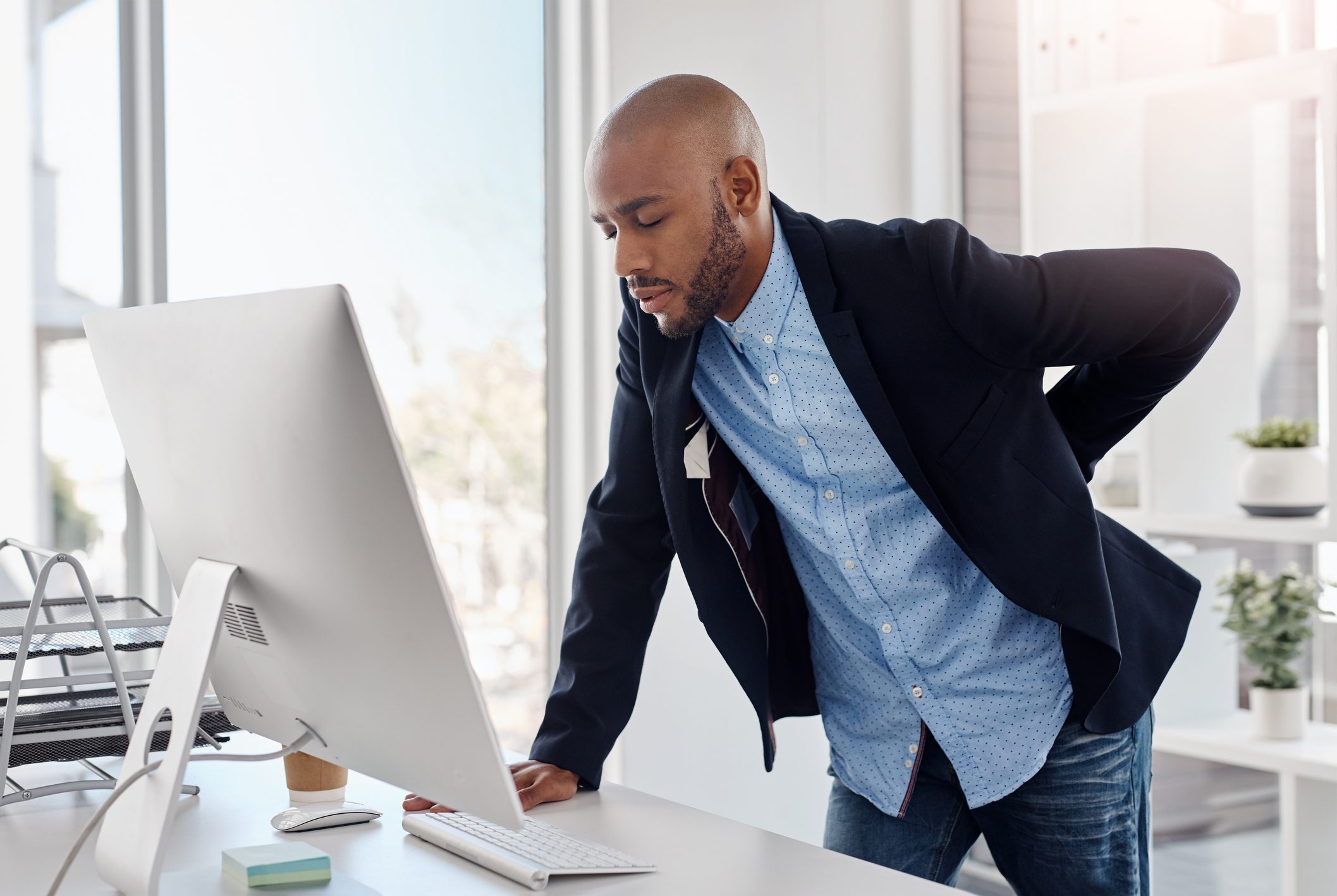 man suffering from back pain at work