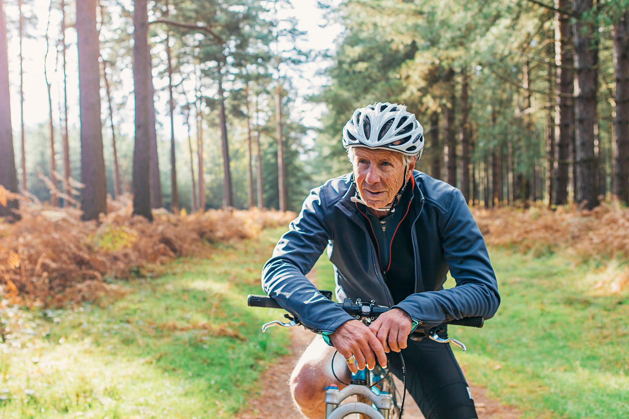 senior man riding bike through forest