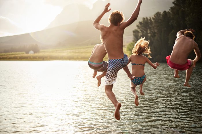 group of friends jumping into the lake on a summer day