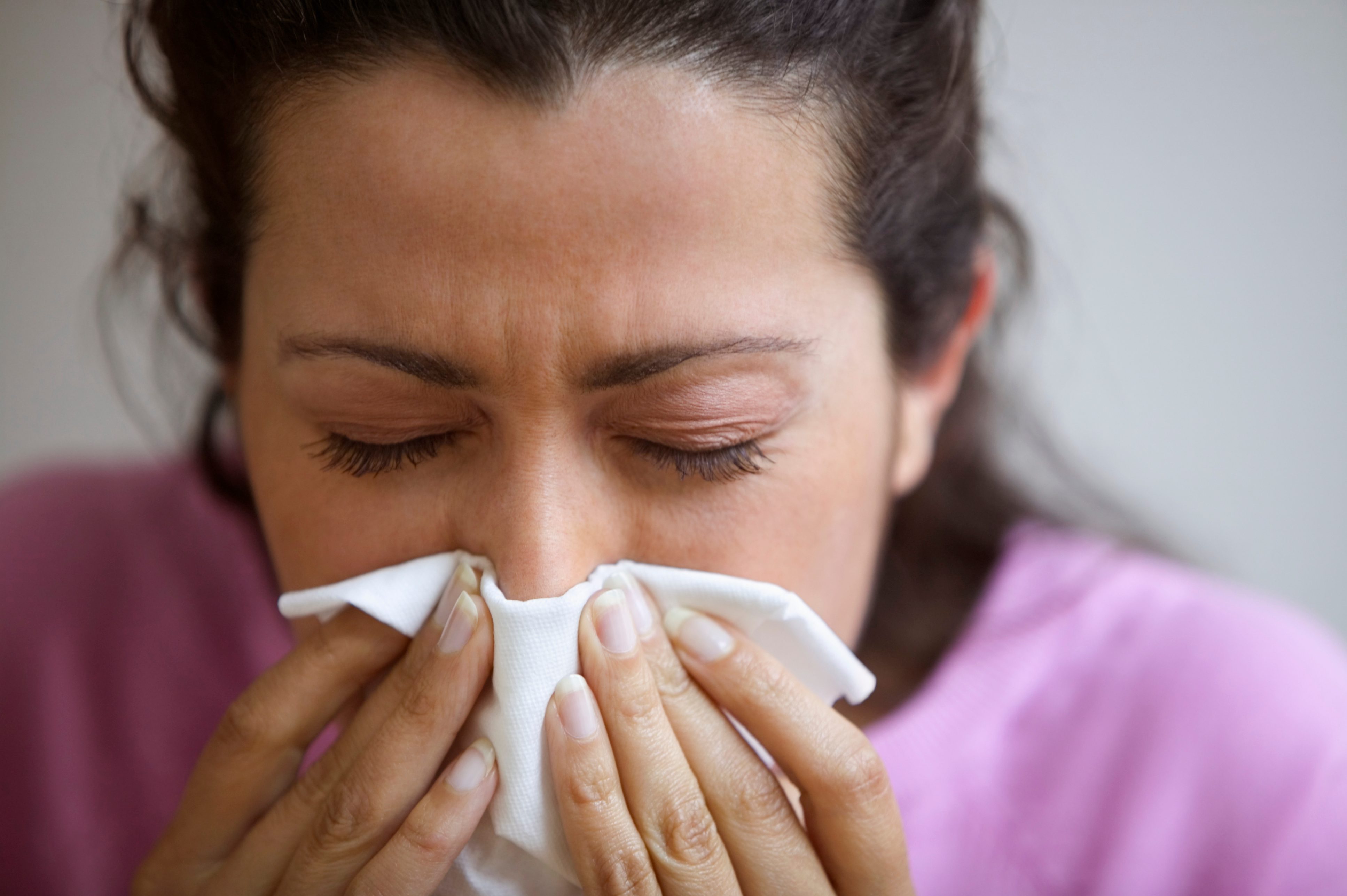 close up of woman blowing nose into tissue