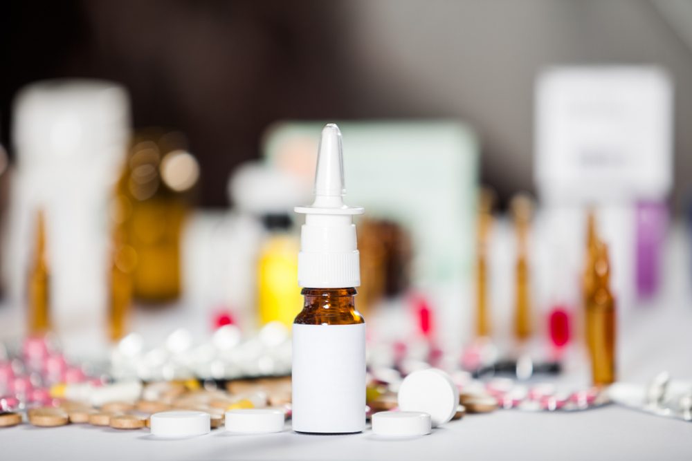 Spray for the nose or a pill to treat colds and gripes glass bottle with medicines. Pharmaceutical medication and medicine pills in packs