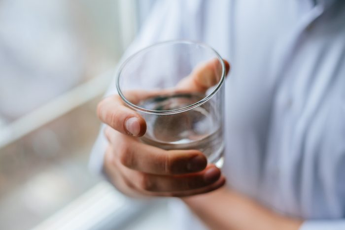 man's hand holding glass with water