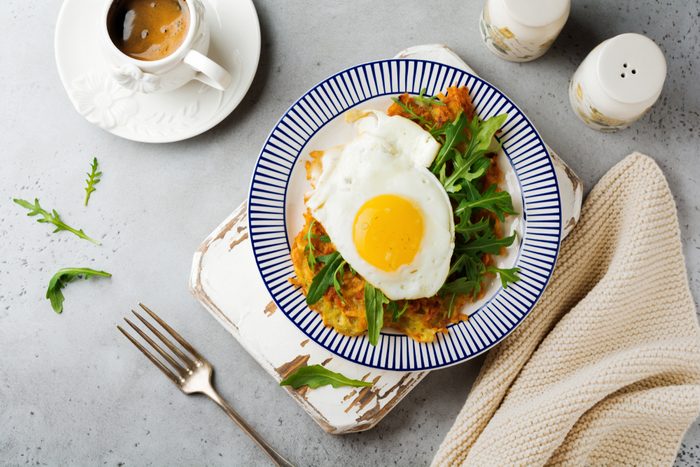 Fried egg with potato pancake, arugula and avocado