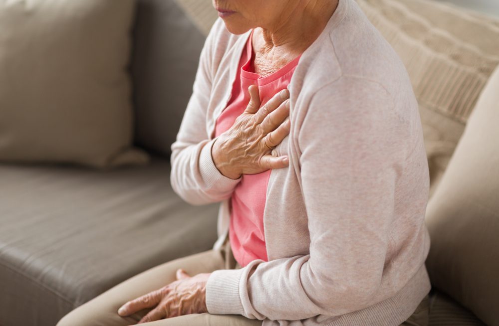 old age, health problem and people concept - close up of senior woman suffering from heartache at home