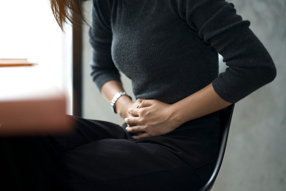 Business woman feeling painful from stomachache illness during working at office, hands touching her stomach and awareness of her Appendicitis sickness. Health insurance care. Insurance concept.