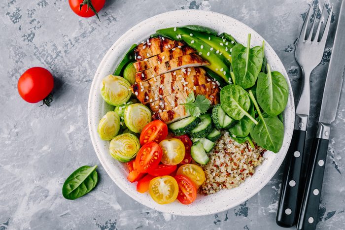 buddha bowl lunch with grilled chicken, quinoa, spinach, avocado, Brussels sprouts, tomatoes, cucumbers
