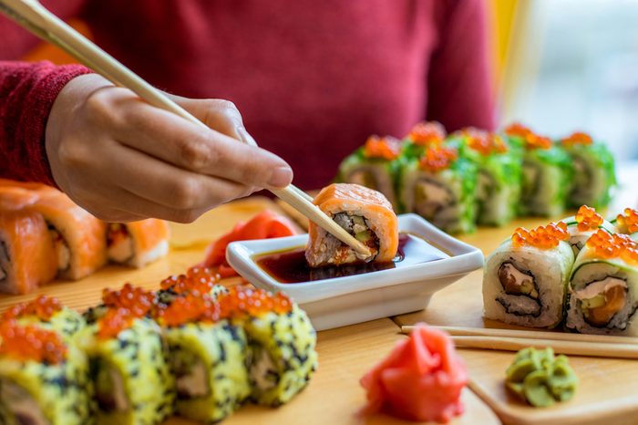 Woman eating sushi rolls at the table