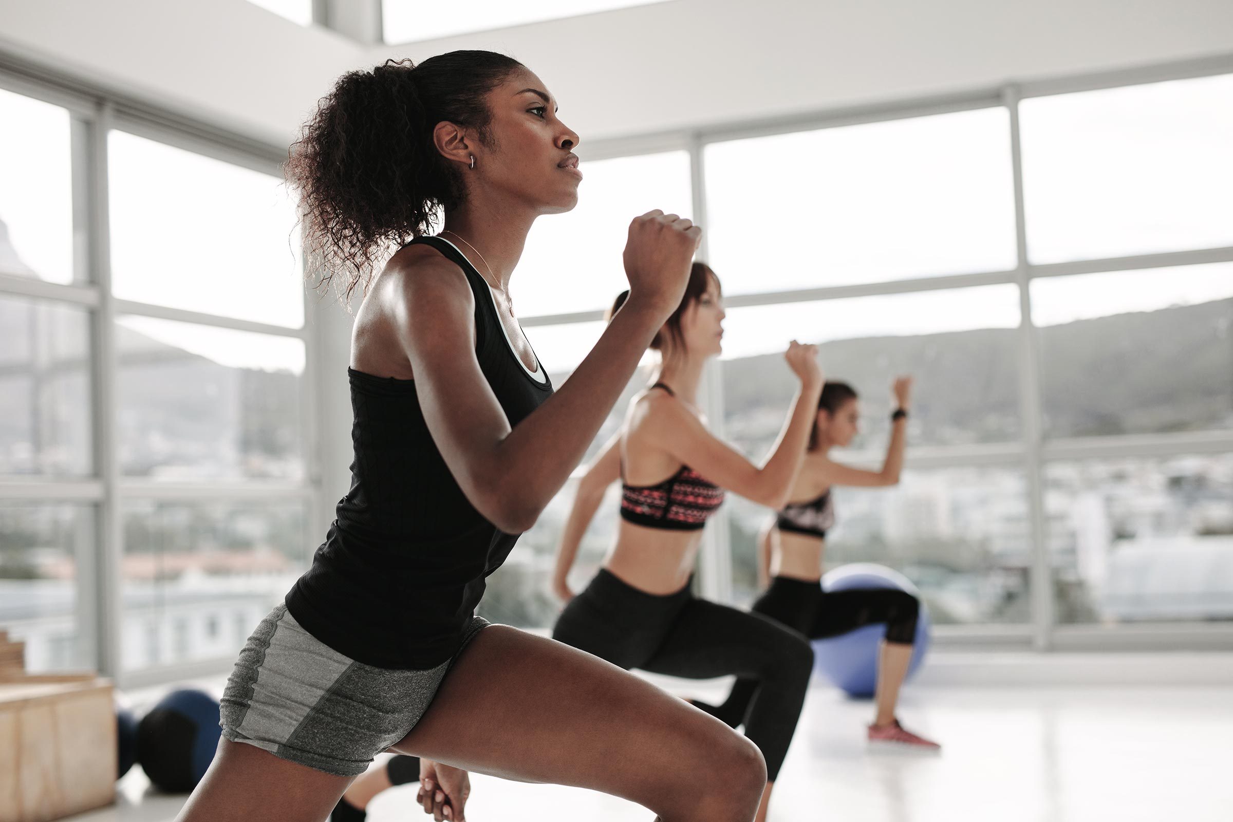 Young woman in sportswear doing exercise during intensive circuit training in gym class. Females working out together in the health studio.
