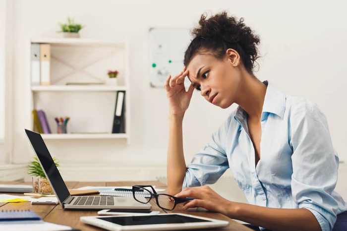 stressed woman working on a laptop computer, hand on head