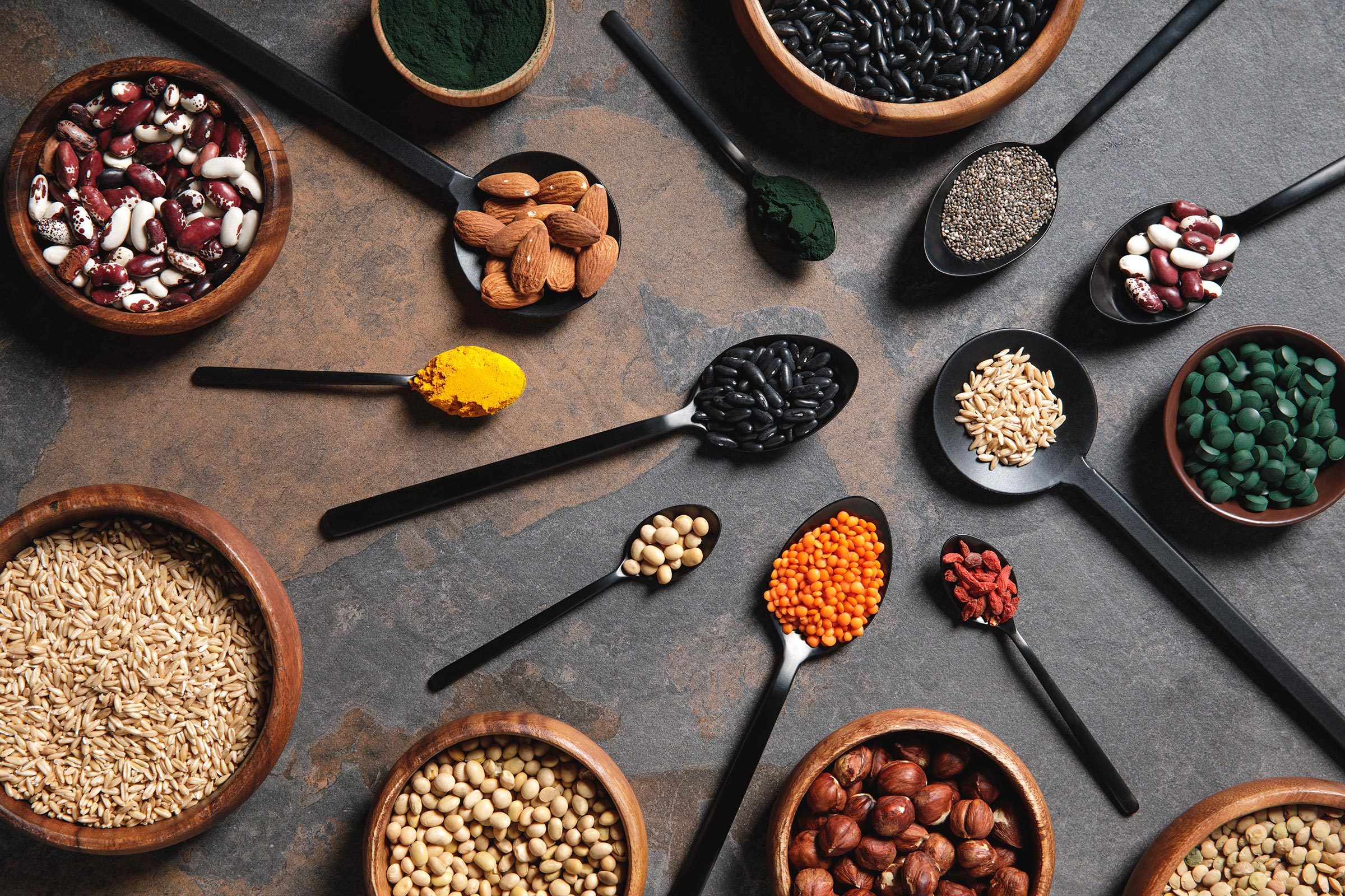 wooden bowls and spoons with superfoods, legumes and grains on table