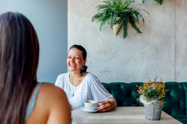 Two happy women talking in cafe. Aged woman and her adult daughter drinking coffee at cafe. Mothers day.