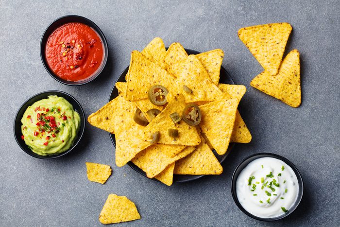 Nachos chips in bowl with sauces, dip variety