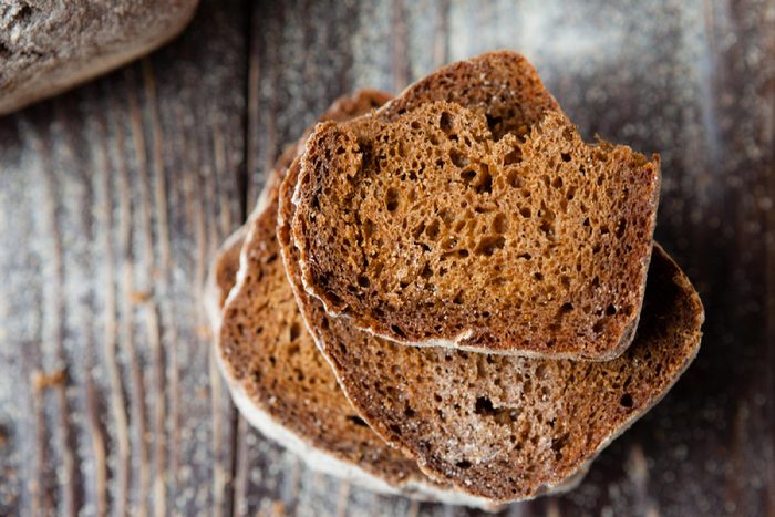 stack of whole grain bread slices on a wooden background