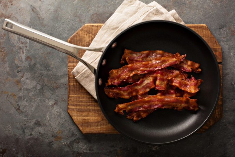 Cooked sizzling hot tasty crispy bacon on a skillet ready for breakfast overhead shot