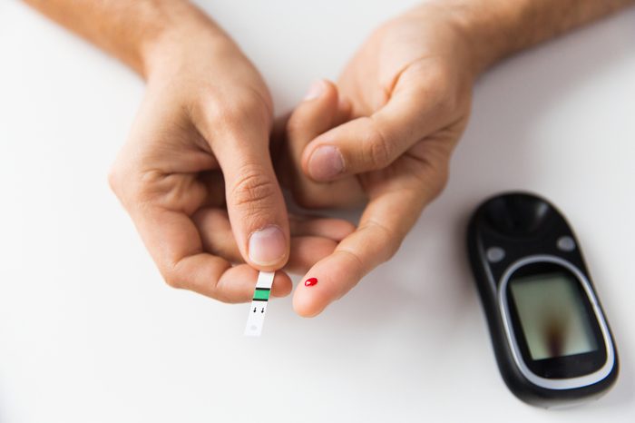 pricked finger with blood, test strip, and glucometer