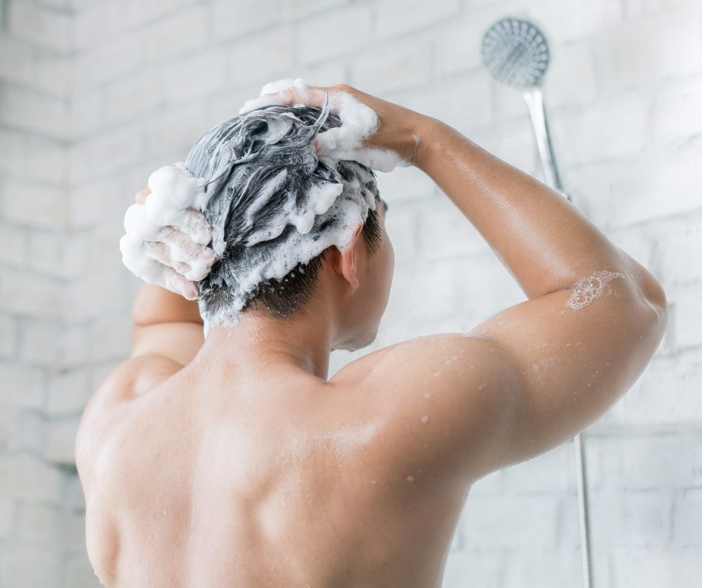 The man is washing his hair, he use shampoo.