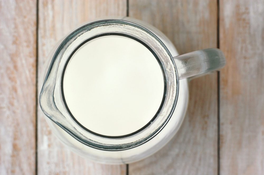 White milk in glass jug on wooden background