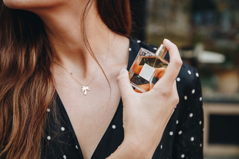 woman applying perfume to her neck