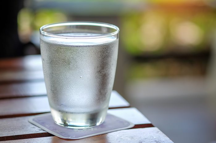 Water glass on wooden table with blurred background.