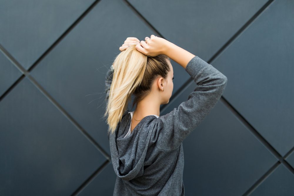 woman putting her hair into a ponytail