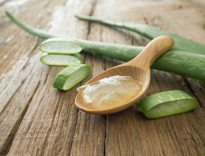 aloe vera gel on wooden spoon with aloe vera on wooden table