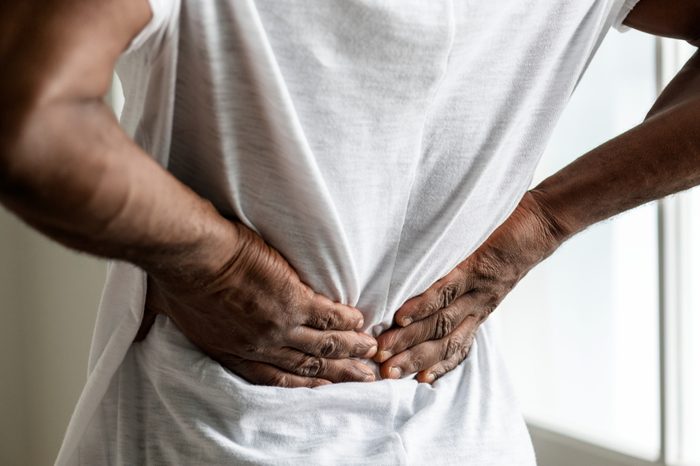 man with hands clutching his lower back