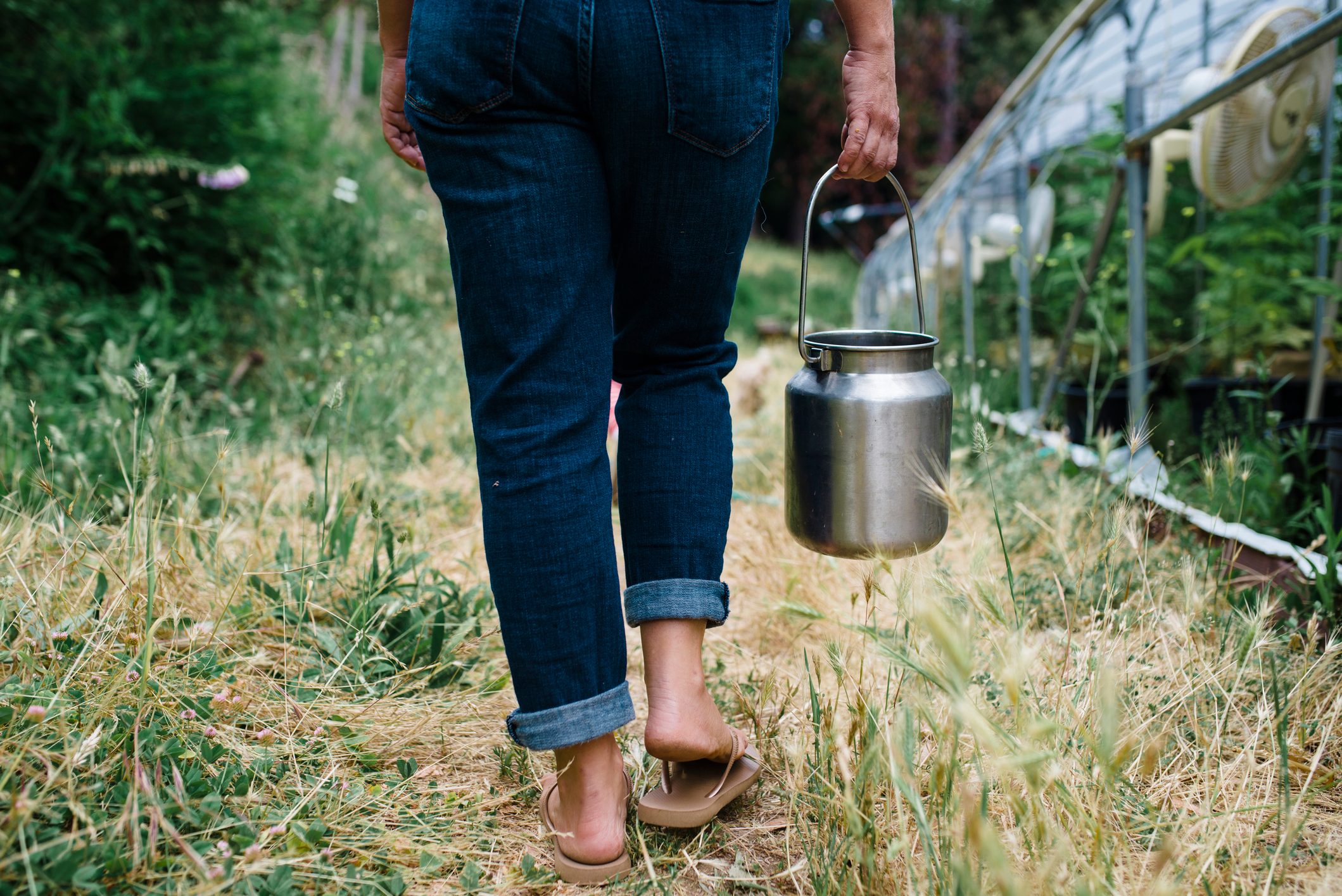 woman walking through field with flip flops on feet