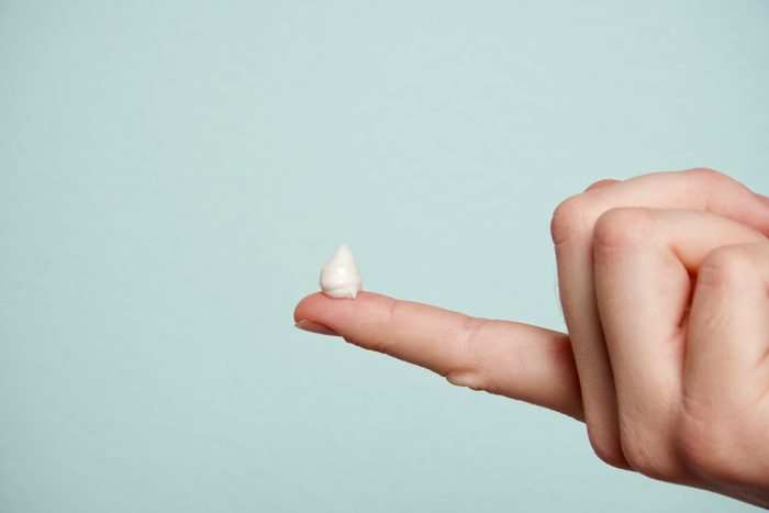 cropped hand with lotion on finger tip