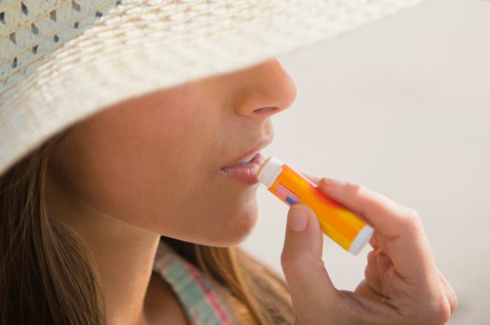 woman applying lip balm sunscreen at the beach
