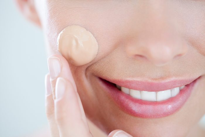 close up of woman applying foundation makeup on face